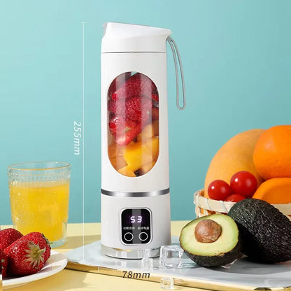 Portable blender with fruits and a glass of juice on a table