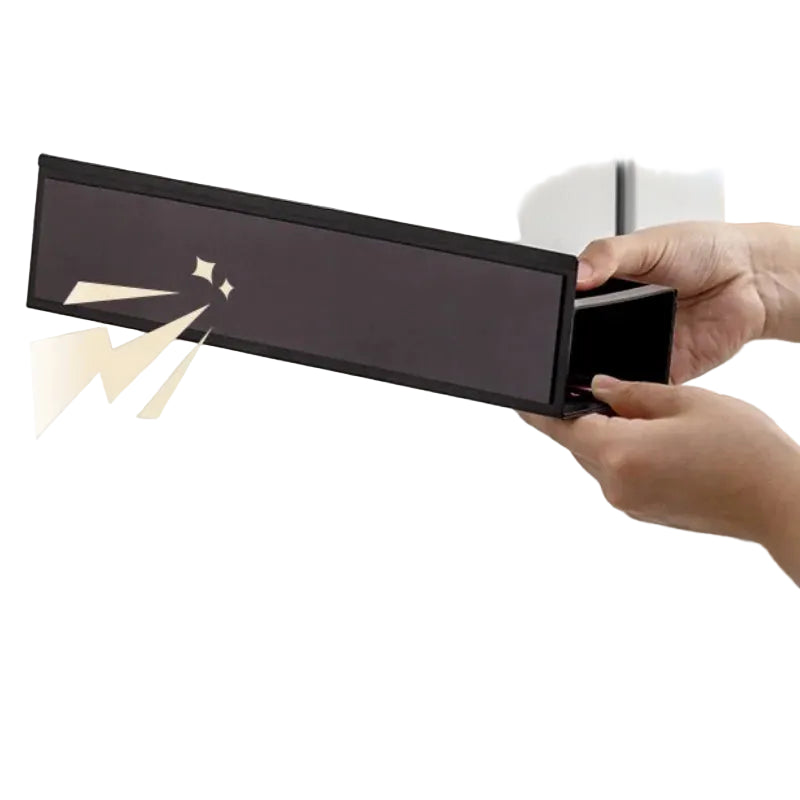 Person opening a black rectangular box with a gold handle on a neutral background