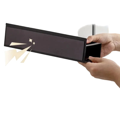 Person opening a black rectangular box with a gold handle on a neutral background